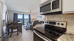 A modern kitchen with a built-in microwave, stove, and oven. There is a dining area with a table and chairs.