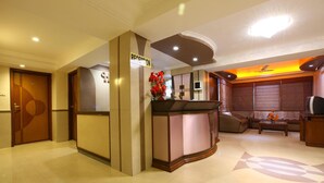 A reception area with a reception desk, a sofa, and a TV. - Hotel Prime (Ahmedabad)