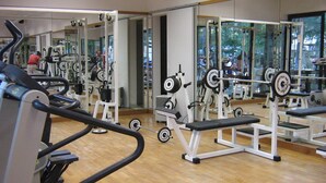 Ein Fitnessstudio mit Cardiogeräten, Gewichten und Bänken.