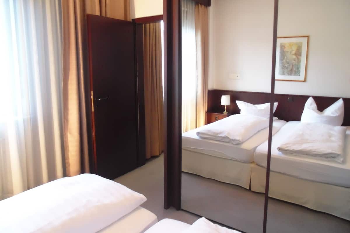 A hotel room with a bed, a nightstand, a lamp, and a painting on the wall.