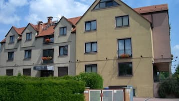 Ein mehrgeschossiges Hotel mit beiger Fassade, zahlreichen Fenstern und Balkonen mit Blumenkästen.