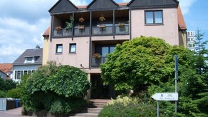 A two-story hotel with a balcony on the upper floor, surrounded by greenery. - As-Salam Aparthotel (Friedrichsdorf)