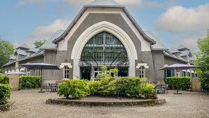 Un edificio con un'ampia entrata ad arco, posti a sedere all'aperto e un cortile in ghiaia.