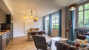 Una cucina moderna con mobili in legno, un'area pranzo con tavolo e sedie, un divano e ampie finestre con tende.