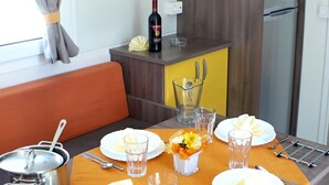 Cozinha compacta com área de jantar, uma garrafa de vinho e uma mesa posta com pratos, copos e talheres.