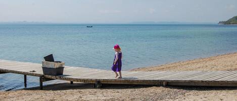 Une jetée en bois s’étendant dans une eau calme, avec une personne debout à son extrémité.