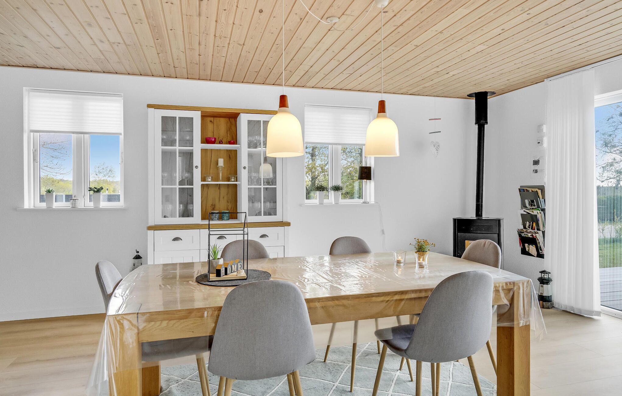 A modern dining area with a wooden table, grey chairs, and pendant lights.