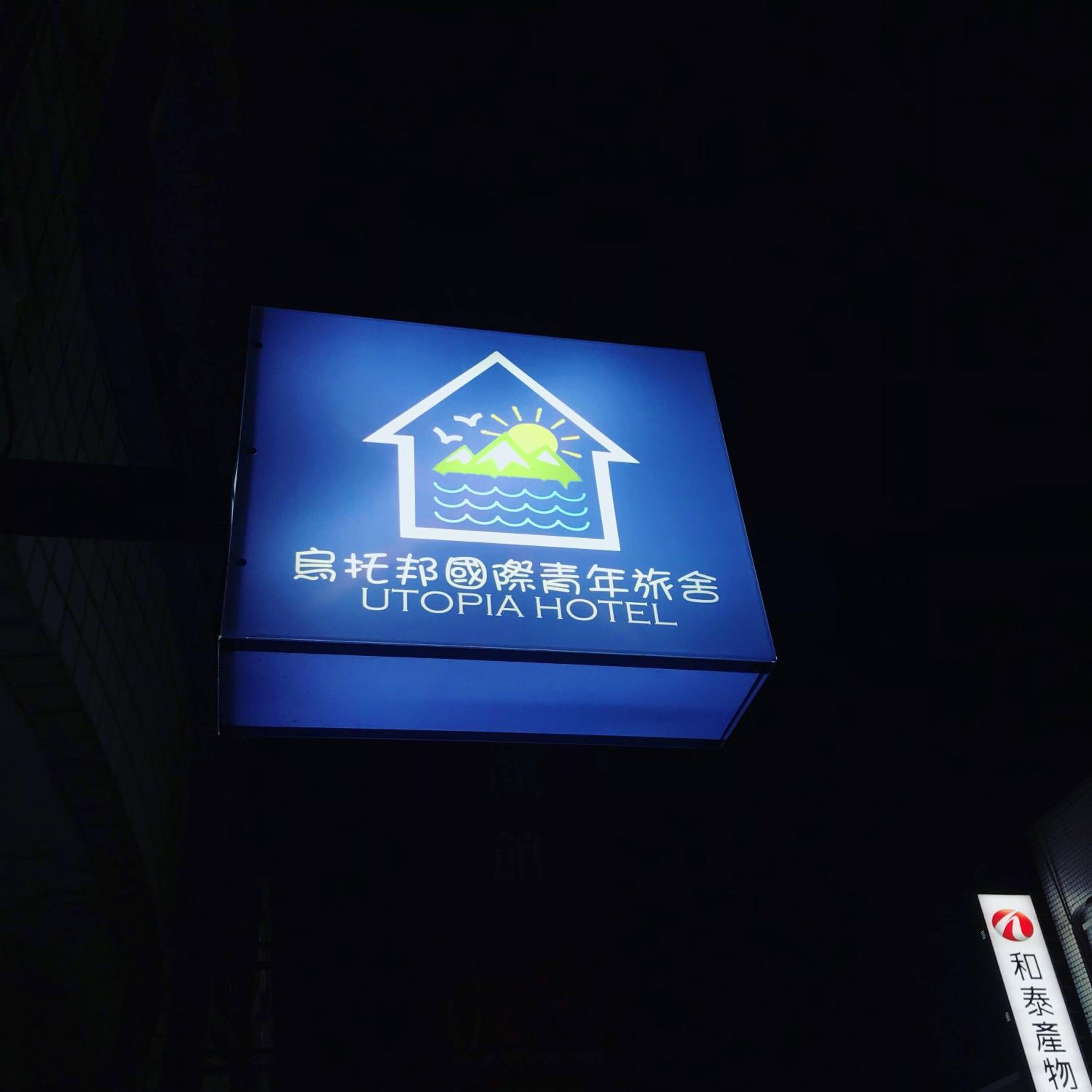 A sign for Utopia Hotel with a house and sun icon, indicating a hotel setting.