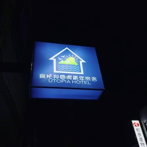 A sign for Utopia Hotel with a house and sun icon, indicating a hotel setting.