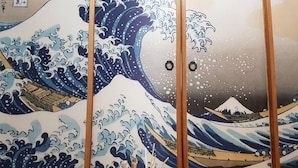 A traditional Japanese room with a wave painting on the wall, a wooden table, and a vase with incense sticks. - Utopia Hostel (Taitung)