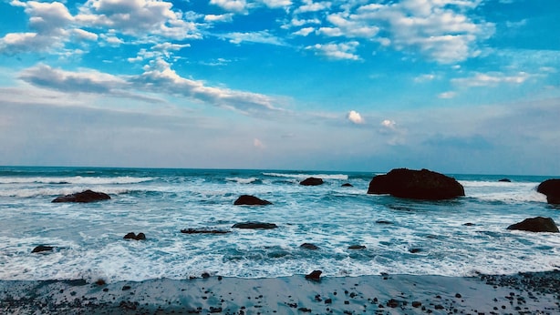 A beach with waves and rocks under a partly cloudy sky. - Utopia Hostel (Taitung)