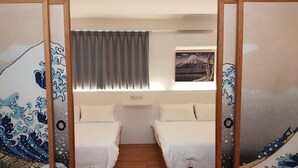 A room with two beds, a window with curtains, a painting of a mountain, and traditional Japanese sliding doors with wave patterns. - Utopia Hostel (Taitung)