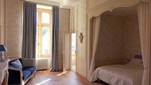 Un dormitorio con cama, sofá y ventana con cortinas.