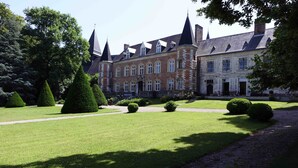 Un edificio grande e histórico con múltiples torres y un jardín bien cuidado.