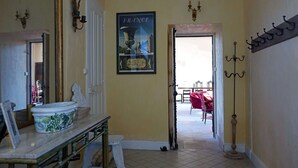Un pasillo con un cartel enmarcado de Francia, un espejo, una mesa con una maceta de cerámica y un perchero.
