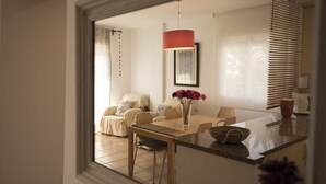 A dining area with a table, chairs, a vase with flowers, and a window with blinds. - bungalow - Formentera (La Savina)
