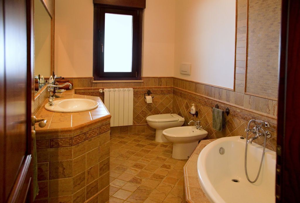 Un baño con una bañera grande, dos inodoros y un bidé.