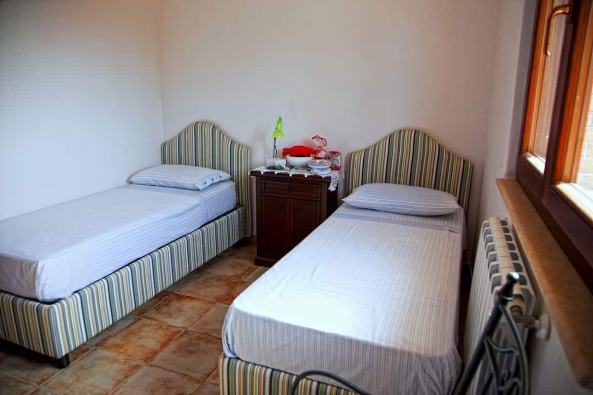 Una habitación pequeña y limpia con dos camas individuales, una mesita de noche y un radiador.