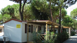 A row of small, single-story cabins with a covered porch, surrounded by trees.