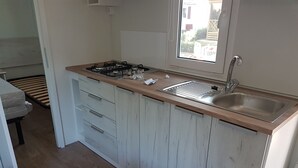 A small kitchen with a wooden countertop, a stainless steel sink, and a window.