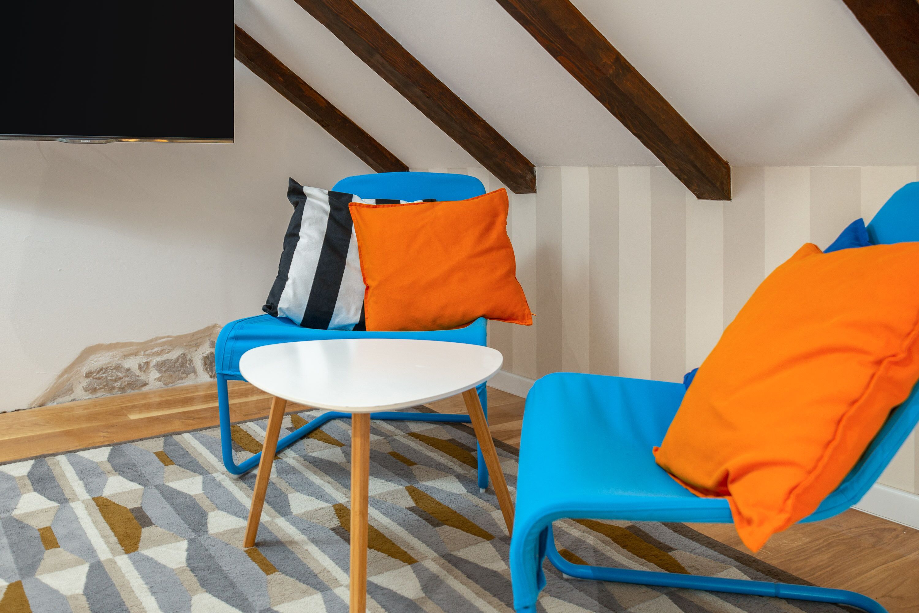 Una habitación con dos sillas azules, una mesa blanca y un tapete estampado.