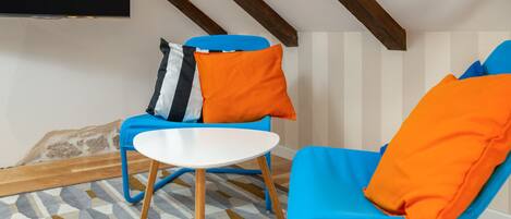 Una habitación con dos sillas azules, una mesa blanca y un tapete estampado.