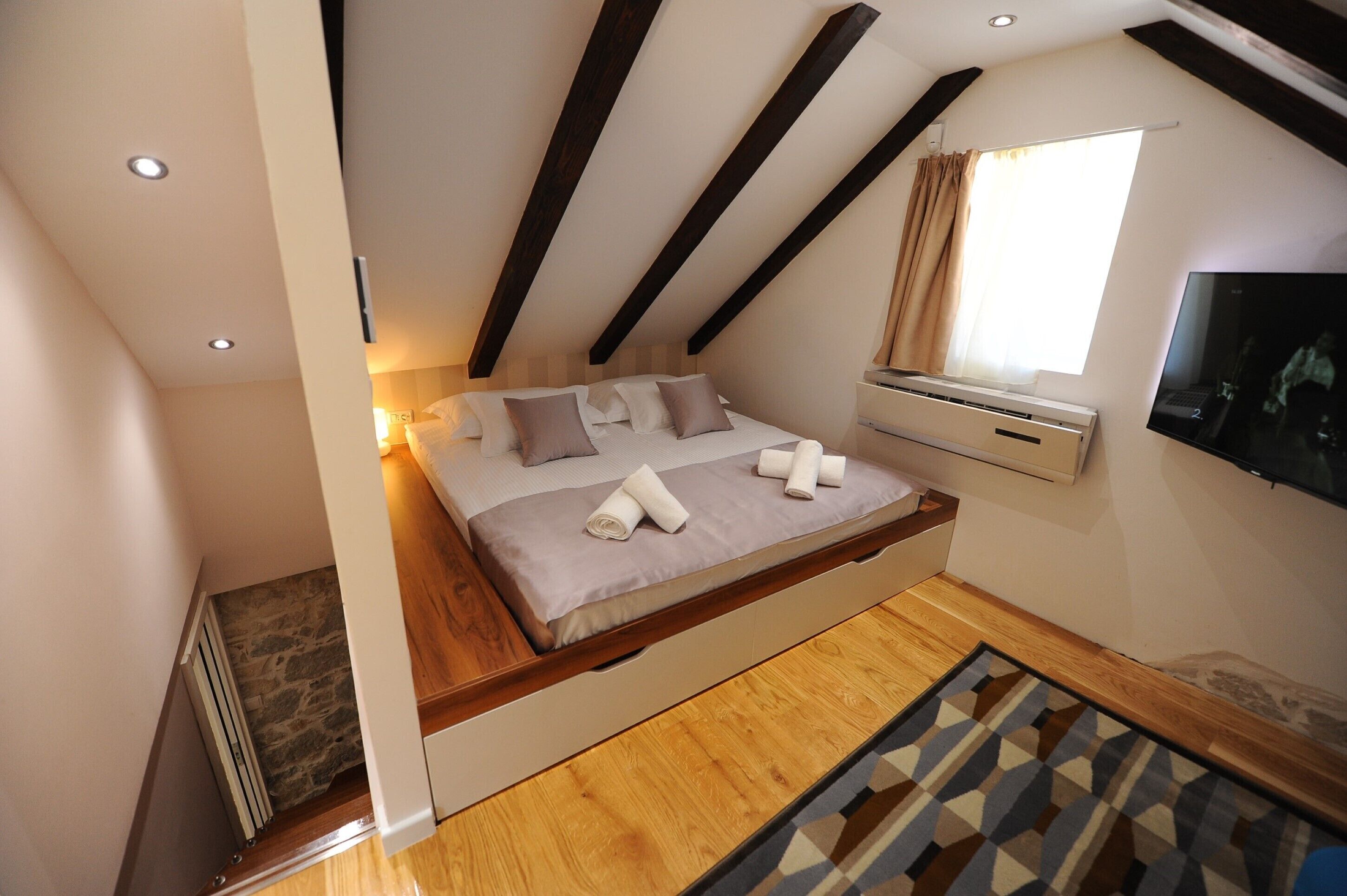 Une chambre à coucher avec un lit, une télévision, une fenêtre et un radiateur.