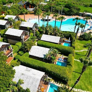 A resort with multiple bungalow-style accommodations, a central swimming pool, and lush tropical landscaping.
