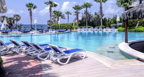 A pool area with lounge chairs and palm trees.