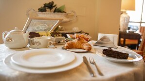 A breakfast setup with a teapot, cups, a croissant, and a slice of cake on a table. - Hotel Ristorante Venezuela (Montesano sulla Marcellana)