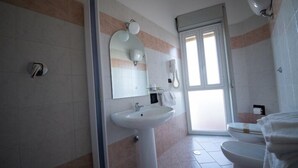 A bathroom with a white sink, a mirror, a toilet, and a shower area. - Hotel Ristorante Venezuela (Montesano sulla Marcellana)