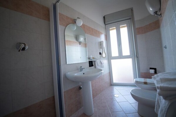 A bathroom with a white sink, a mirror, a toilet, and a shower area.