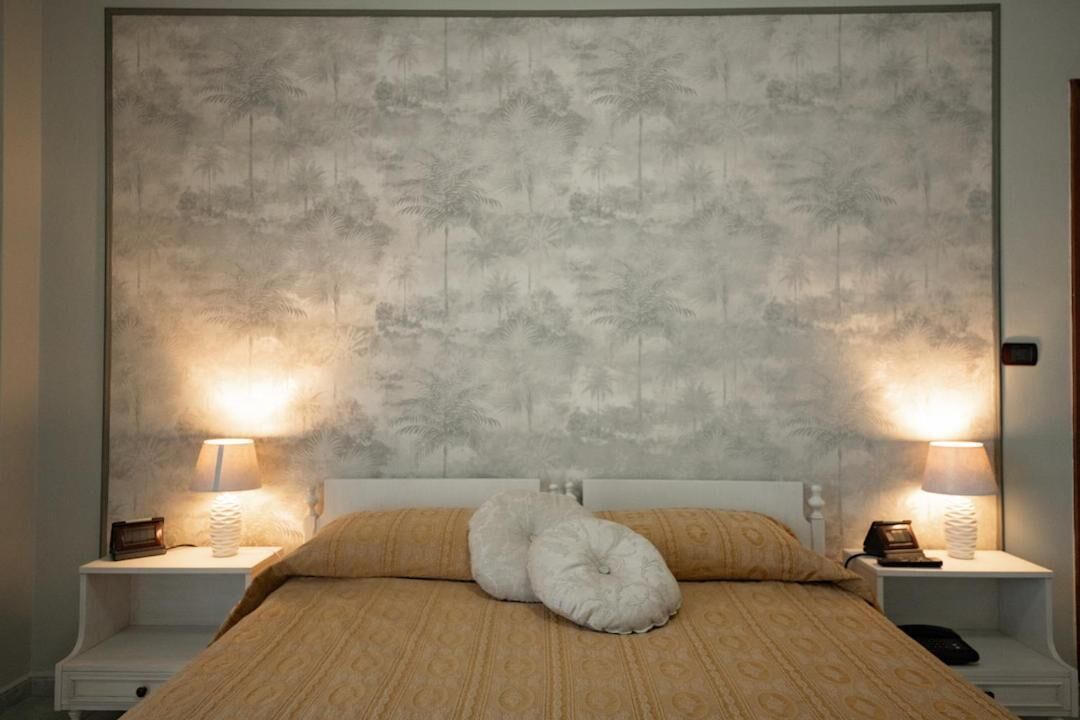 A bedroom with a large bed, two bedside tables with lamps, and a headboard with a palm tree pattern.