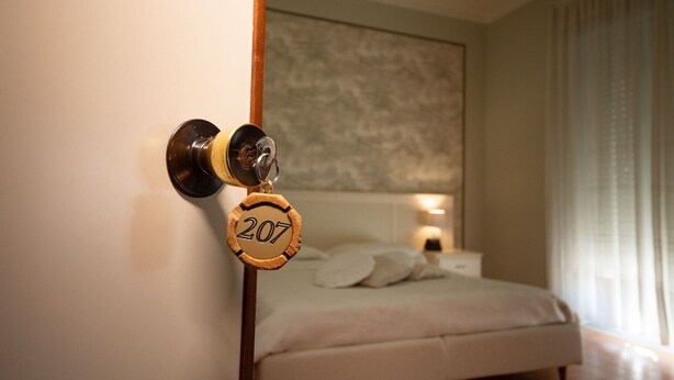 A hotel room with a bed, a nightstand, and a wall-mounted lamp. - Hotel Ristorante Venezuela (Montesano sulla Marcellana)