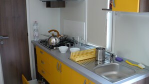 A compact kitchen with a gas stove, a sink, and yellow cabinets.