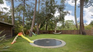 A backyard with a trampoline, a slide, and a hammock. - Villa Takamira - heated pool and spacious garden close to Golf and Beaches (Soorts-Hossegor)
