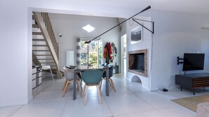 A modern living room with a dining area, a fireplace, and a TV. - Villa Takamira - heated pool and spacious garden close to Golf and Beaches (Soorts-Hossegor)