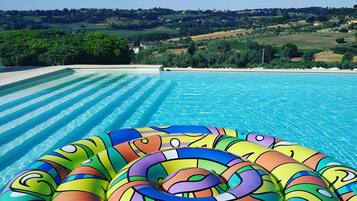 Una piscina con acqua cristallina e un colorato materassino gonfiabile in primo piano.