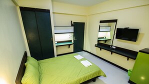 Una habitación con cama, armario, espejo y televisor.