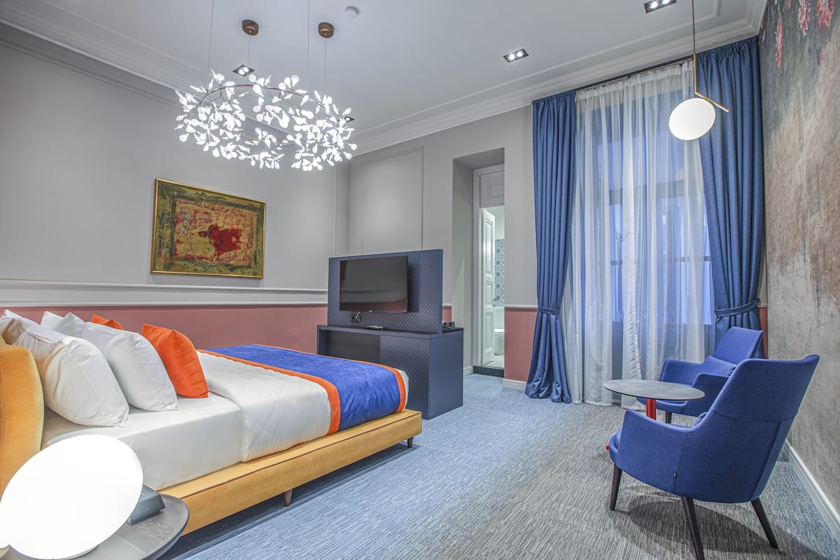 A hotel room with a bed, a TV, a desk, and a chair.