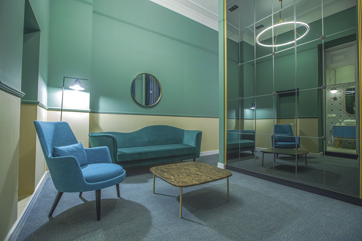 A modern waiting area with a teal sofa, matching armchairs, and a coffee table.
