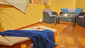 Una stanza accogliente con un letto, un tavolino con un bicchiere di succo e due divani con cuscini.