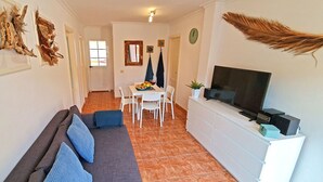 Un soggiorno con divano, televisore e zona pranzo con sedie e tavolo.