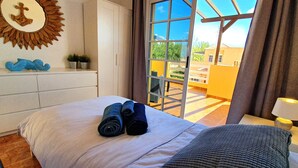 Una camera d'albergo con un letto, una finestra vista esterna, un comò e una lampada.