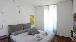 Un lit bien fait, avec des oreillers, une table de chevet, une lampe, une armoire et une fenêtre avec des rideaux.