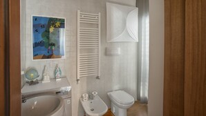 Une salle de bain équipée de toilettes, d’un bidet, d’un lavabo et d’un porte-serviettes.