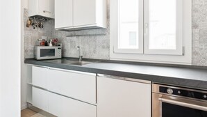 Una cucina moderna con mobili bianchi, un forno a microonde, una lavastoviglie e una finestra con vista.