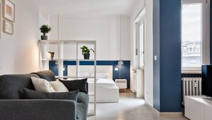 A modern living room with a sofa, a bed, a white cabinet, and a window with a view. - GuestHost - Comfortable studio perfect for 2 guests is located near the famous Parco del Valentino with the beautiful castle and the medieval village, a few subway stops from the historic center, near the famous Eataly, the Lingotto, the Molinette Hospit (Torino)