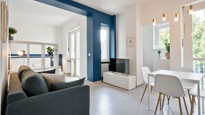 A modern living room with a sofa, TV, dining table, and chairs. - GuestHost - Comfortable studio perfect for 2 guests is located near the famous Parco del Valentino with the beautiful castle and the medieval village, a few subway stops from the historic center, near the famous Eataly, the Lingotto, the Molinette Hospit (Torino)