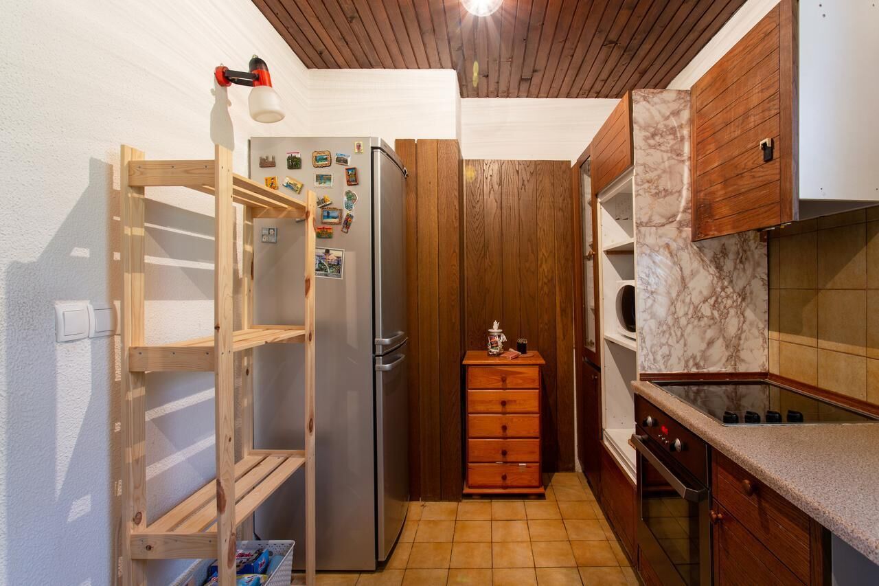Una cocina compacta con armarios de madera, horno empotrado y refrigerador.